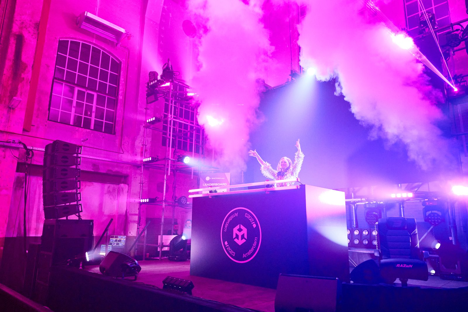 DJ performing on stage with lasers and smoke effects